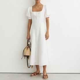 Model wearing Reiss white midi dress with square neckline and puff sleeves, styled with tan sandals and a small beige bag.