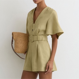Model wearing Reiss green short-sleeve belted playsuit with V-neck and flared sleeves, carrying a woven straw bag