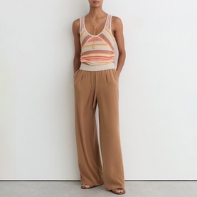 Model wearing Reiss beige wide-leg trousers, styled with a striped knit vest top and gold necklace.