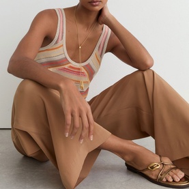 Model wearing Reiss beige striped knit tank top with wide-leg trousers and brown leather sandals, gold necklace