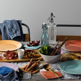 Royal Doulton multicolour dinnerware set styled on a linen-draped table with charcuterie, vegetables, glassware and wooden serving boards.