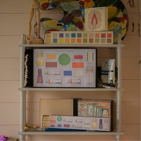 Archivist gift box set displayed on a white wooden shelf alongside art supplies, paint palettes, and decorative items in a styled home setting.