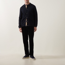 Model wearing Barbour Navy cardigan with check shirt lining detail, styled with black trousers and navy trainers.