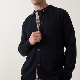 Model wearing Barbour Navy cardigan with button-front placket, revealing a tan check shirt lining underneath.