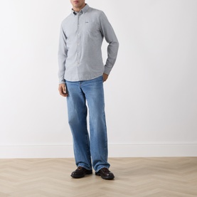 Model wearing Barbour navy casual shirt in 100% cotton with light blue wide-leg jeans and dark loafers