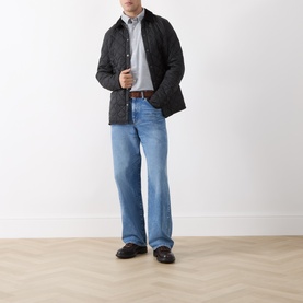 Model wearing Barbour navy casual shirt with black quilted jacket, light blue jeans, and brown loafers.