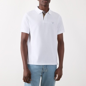 Model wearing Barbour white cotton polo shirt with contrast collar detail, styled with light blue jeans