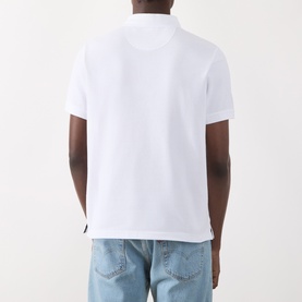 Model wearing Barbour white cotton polo shirt, back view, styled with light blue jeans