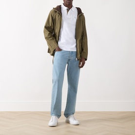 Model wearing Barbour White polo shirt, styled with olive zip-up jacket, light blue jeans and white trainers.