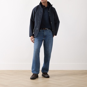 Model wearing Barbour Navy polo, styled with dark wax jacket, mid-wash straight jeans and dark loafers.
