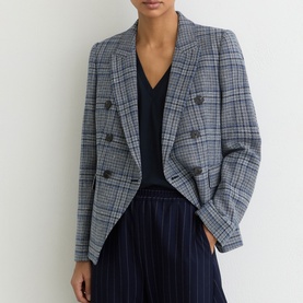 Model wearing Reiss navy check double-breasted blazer, styled with a black top and navy pinstripe trousers.