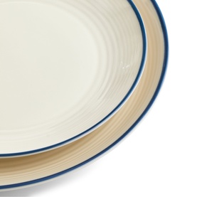 Gordon Ramsay stacked ceramic plates in cream with blue rim detail, showing ridged texture on outer edge