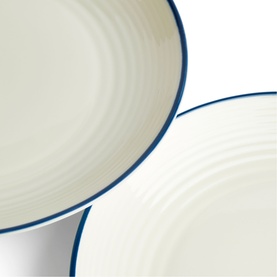 Gordon Ramsay blue-rimmed cream ceramic plates, close-up showing textured surface and navy border detail, two plates overlapping