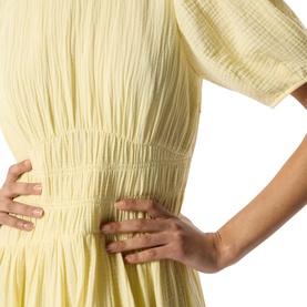 Model wearing Whistles yellow dress, close-up showing textured fabric with elasticated shirred waist detail