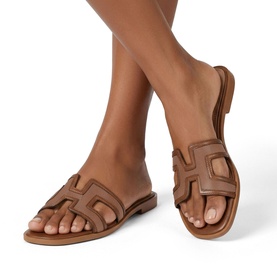 Model wearing Steve Madden brown leather flat slide sandals with cut-out H-strap detail and tan sole