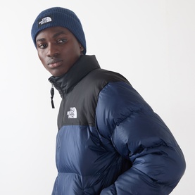 Model with North Face Box Logo Knitted Beanie in Summit Navy, ribbed knit with fold-up brim, styled with matching navy puffer jacket.