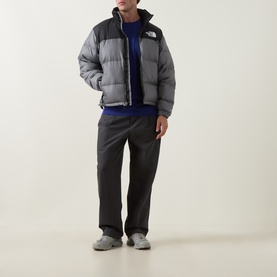 Model wearing North Face Smoked Pearl and TNF Black nylon casual jacket, styled with blue sweatshirt and dark grey trousers.