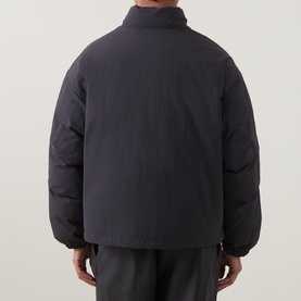 Model wearing North Face Casual Jacket in Obsidian, rear view showing quilted puffer design with high collar, styled with dark trousers.