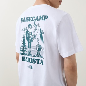Model wearing North Face white crew neck T-shirt, back view showing teal Basecamp Barista graphic print.