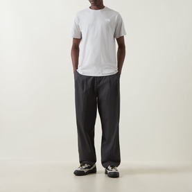 Model wearing North Face Evolution Box Logo Back Graphic T-Shirt in Cumulus Cloud, styled with dark wide-leg trousers and trail shoes.