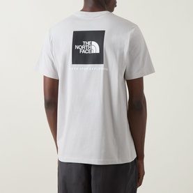 Model wearing North Face Evolution Box Logo Back Graphic T-Shirt in Cumulus Cloud, showing black square back logo print, paired with grey joggers.