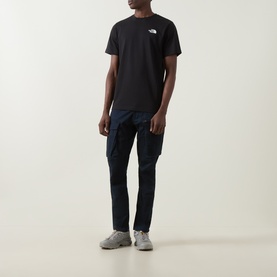 Model wearing North Face Evolution Box Logo Back Graphic T-Shirt in black, styled with navy trousers and grey trainers.