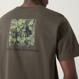 Model wearing North Face Yosemite Oak Graphic T-Shirt in New Taupe Green, showing camouflage square logo and Never Stop Exploring slogan on back.