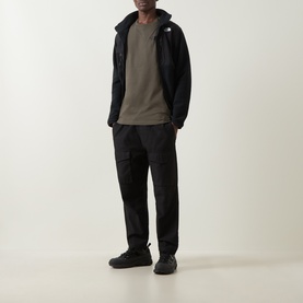 Model wearing North Face Yosemite Oak Logo Back Graphic T-Shirt in New Taupe Green, styled with black zip-up jacket and dark cargo trousers.