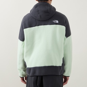 Model wearing North Face fleece in Calcified Lime and Anthracite colourblock, hooded, with logo patch at back shoulder.