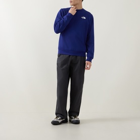 Model wearing North Face Bold Blue crew neck sweatshirt with small chest logo, styled with dark trousers and trail trainers.