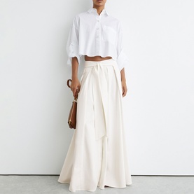 Model wearing Reiss white wide-leg trousers with tie waist, styled with a white cropped shirt and brown bag
