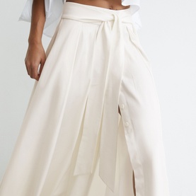 Model wearing Reiss white wide-leg trousers with tie-waist detail and front pleat, styled with a white crop top.