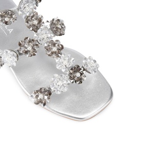Silver flat sandal detail shot showing crystal and metallic floral embellishments across straps, square open toe, smooth silver footbed