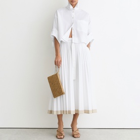 Model wearing Reiss white midi dress with sheer hem detail, styled with woven clutch bag and strappy sandals