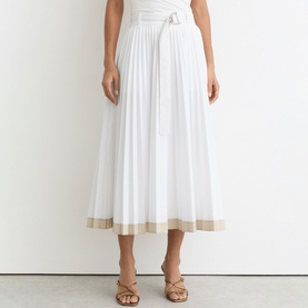 Model wearing Reiss white pleated midi skirt with contrast hem trim and self-belt, styled with gold strappy sandals