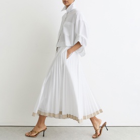 Model wearing Reiss white pleated midi skirt with gold hem trim, styled with matching white shirt and gold strappy heeled sandals