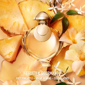 Paco Rabanne Olymp&eacute;a Elixir Eau de Parfum Intense bottle surrounded by pineapple slices and tropical flowers, fruity gourmand fragrance visual