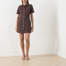 Model wearing Paige Rich Chocolate cotton mini shirt dress with short sleeves, button-front fastening and patch pockets, styled with nude heeled