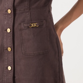 Model wearing Paige dress in Rich Chocolate, close-up of chest pocket with gold logo hardware and gold snap buttons, cotton fabric.