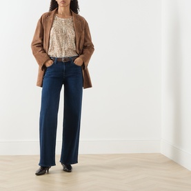 Model wearing Paige Straight Jeans in Basillica dark indigo denim, styled with a brown coat and floral top.