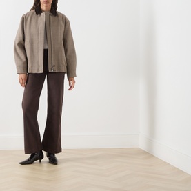 Model wearing Paige Rich Chocolate wide leg jeans styled with a taupe bomber jacket and black heeled boots.