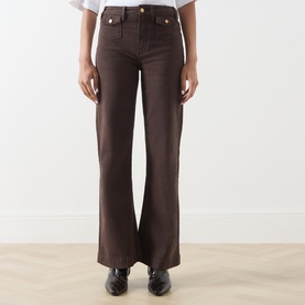Model wearing Paige Wide Leg Jeans in Rich Chocolate, styled with black leather shoes. High-rise waist, gold-tone buttons.