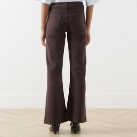 Model wearing Paige Wide Leg Jeans in Rich Chocolate, rear view, showing flared silhouette and back pockets, styled with black heeled boots.