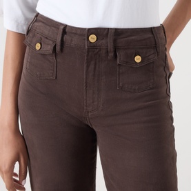 Model wearing Paige Wide Leg Jeans in Rich Chocolate with gold-tone buttons on front patch pockets, paired with a white top.