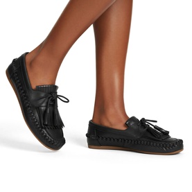 Model wearing black leather moccasin loafers with tassel lace detail, whipstitch trim, and tan rubber sole