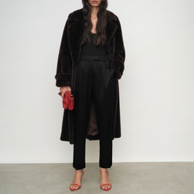 Model wearing Reiss black long faux fur coat, styled with black tailored trousers, red heeled sandals and small red bag.