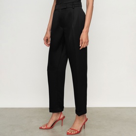 Model wearing Reiss black tailored tapered trousers with front pleat detail, styled with red heeled sandals.