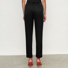 Model wearing Reiss black straight-leg trousers, back view, styled with red heeled mules.
