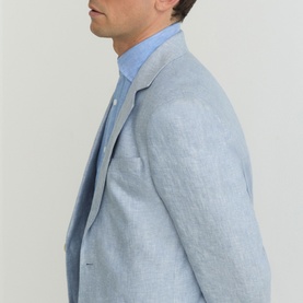 Model wearing Reiss soft blue linen blazer, styled with a light blue shirt, side profile view