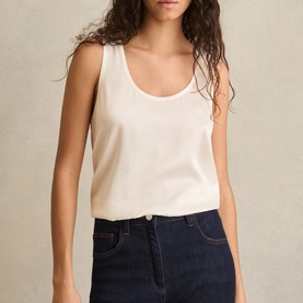 Model wearing Reiss white sleeveless vest top with scoop neck, styled with dark navy denim mini skirt.